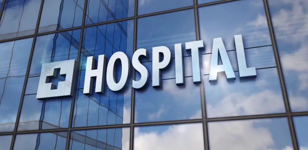 the word hospital is reflected in a glass building